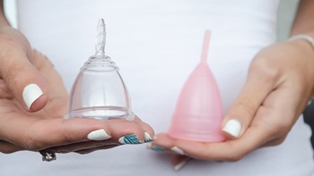 primo piano mani con 2 coppette mestruali